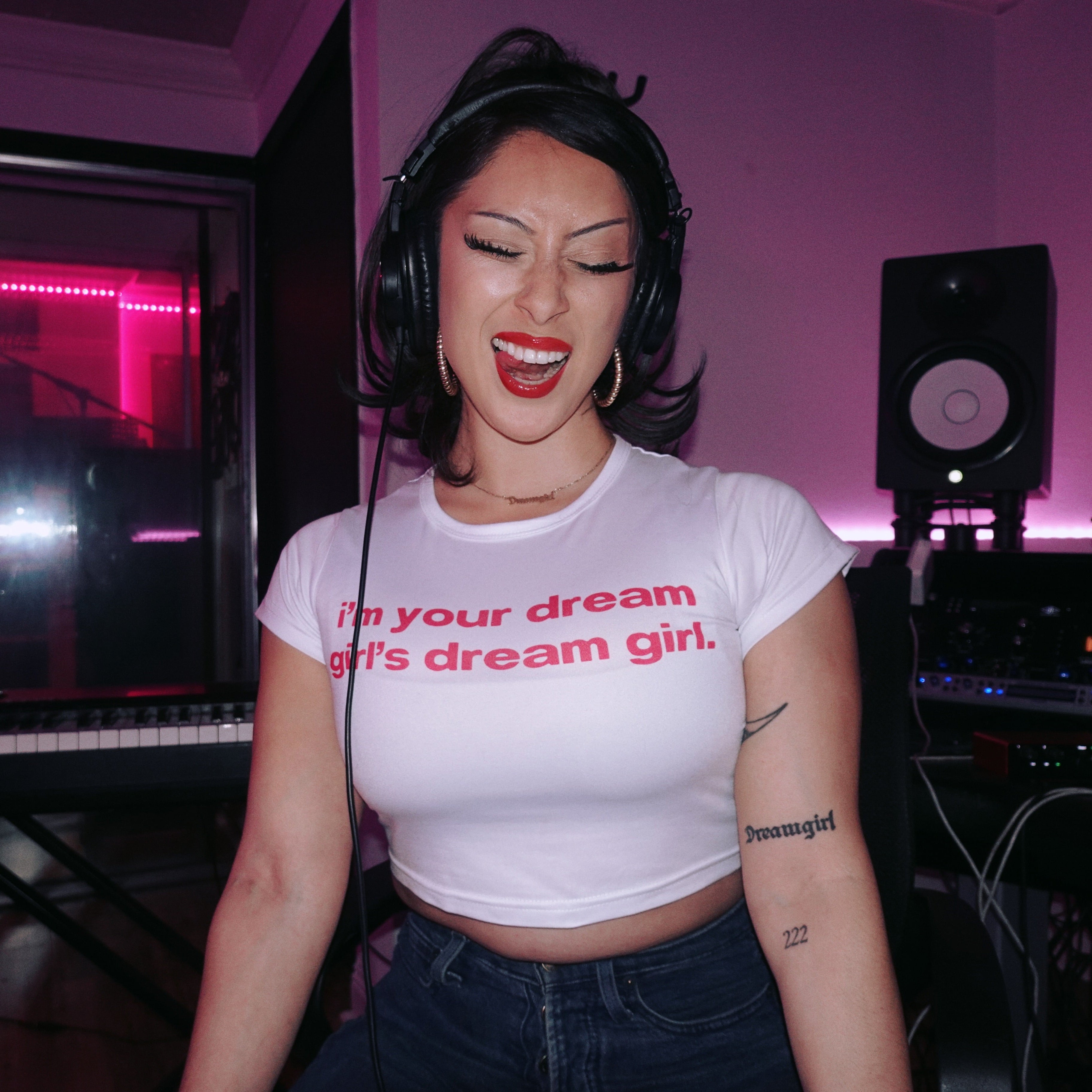 Person wearing headphones and a white t-shirt with text in a music studio.